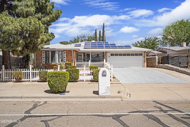 ranch-style house with an attached garage, solar panels, driveway, and brick siding