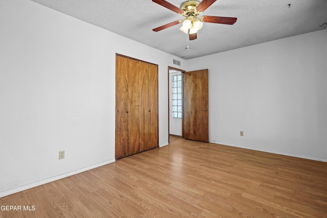unfurnished bedroom with wood finished floors, a textured ceiling, baseboards, a closet, and a ceiling fan