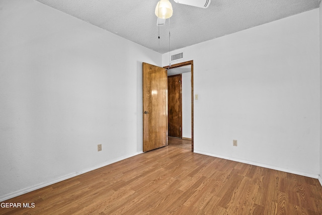 empty room with ceiling fan, wood finished floors, baseboards, and a textured ceiling