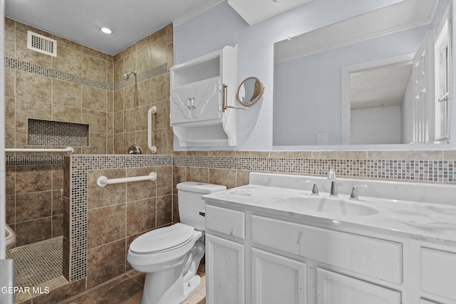 full bathroom with tiled shower, toilet, vanity, and tile walls