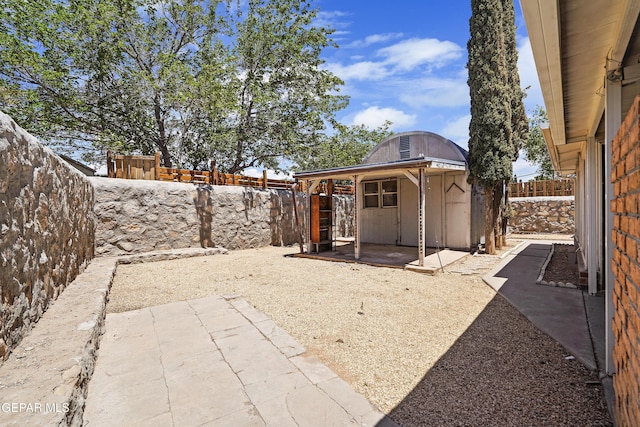 fenced backyard with a patio area and an outbuilding