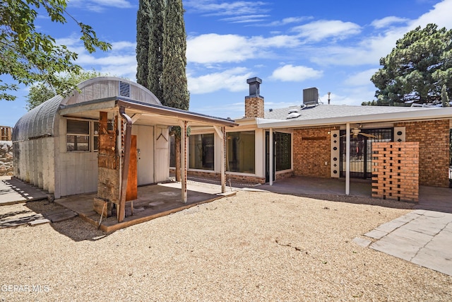 back of house featuring a patio area, a ceiling fan, a chimney, and brick siding