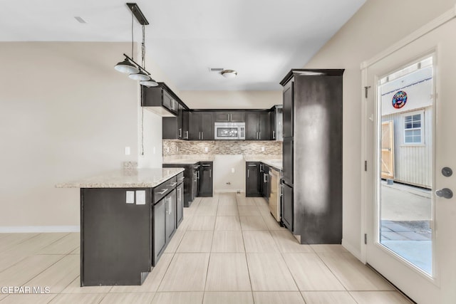 3096 Java Chip Pl, El Paso, TX 79938 - kitchen featuring stainless steel microwave, tasteful backsplash, light stone countertops, pendant lighting, and dark brown cabinetry