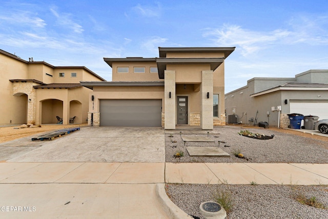 14740 Jack White Ave, El Paso, TX 79938 - view of front facade with stucco siding, driveway, stone siding, central AC, and an attached garage