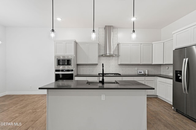 14740 Jack White Ave, El Paso, TX 79938 - kitchen featuring appliances with stainless steel finishes, wall chimney exhaust hood, dark countertops, decorative backsplash, and light wood finished floors