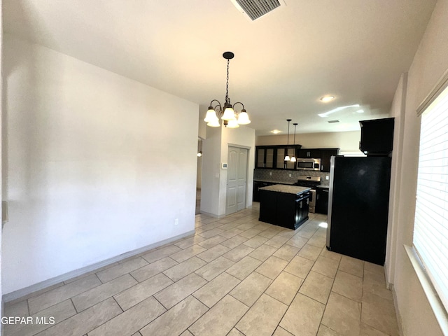 13192 Lost Willow, El Paso, TX 79938 - kitchen with appliances with stainless steel finishes, dark cabinets, backsplash, a kitchen island, and a chandelier