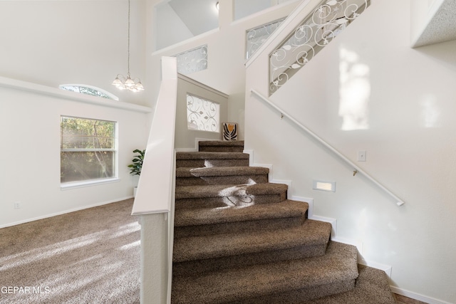 stairs featuring a chandelier, a high ceiling, baseboards, and carpet