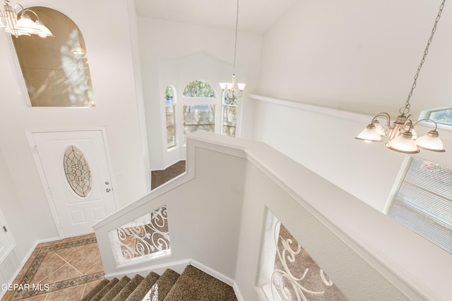 stairs with a chandelier, inlaid floor details, and plenty of natural light