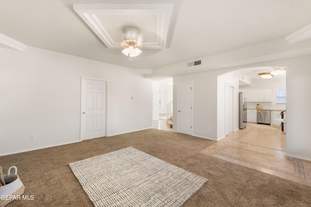 unfurnished living room with a ceiling fan, light carpet, arched walkways, stairway, and baseboards