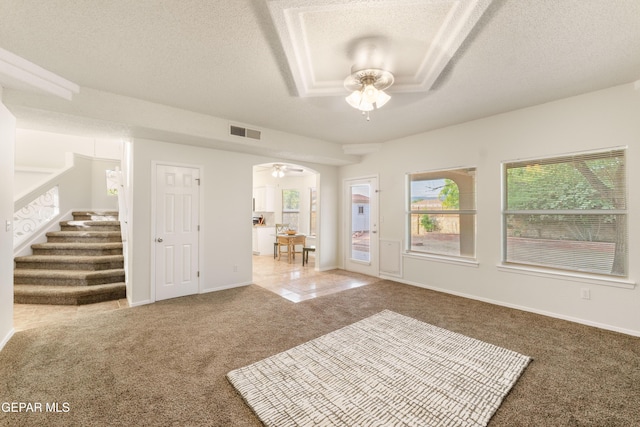 living area featuring a ceiling fan, carpet, a textured ceiling, stairway, and baseboards