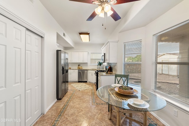 kitchen with stainless steel appliances, inlaid floor details, baseboards, white cabinets, and a ceiling fan