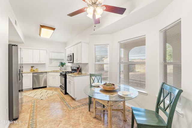 kitchen featuring appliances with stainless steel finishes, decorative backsplash, white cabinets, and healthy amount of natural light