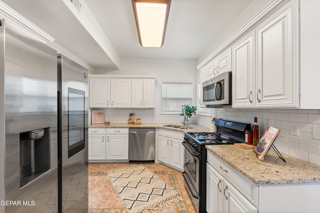 kitchen with stainless steel appliances, tasteful backsplash, white cabinetry, and light stone countertops