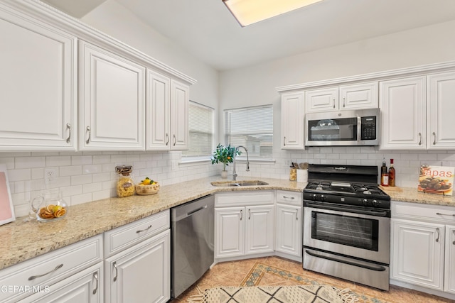 kitchen featuring stainless steel appliances, a sink, white cabinets, and tasteful backsplash