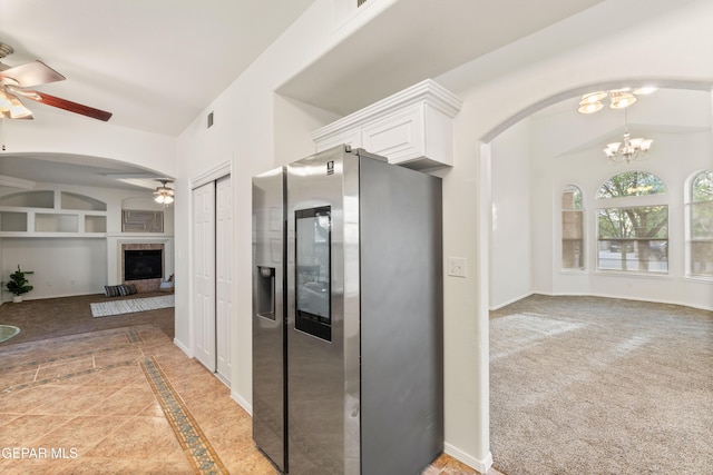 kitchen featuring stainless steel fridge with ice dispenser, a ceiling fan, open floor plan, and arched walkways