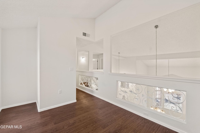 spare room featuring wood finished floors, high vaulted ceiling, and baseboards