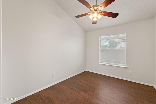 empty room featuring lofted ceiling, dark wood-type flooring, baseboards, and a ceiling fan