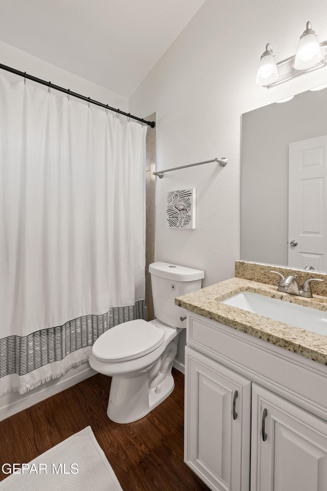 bathroom featuring wood finished floors, toilet, vanity, and curtained shower