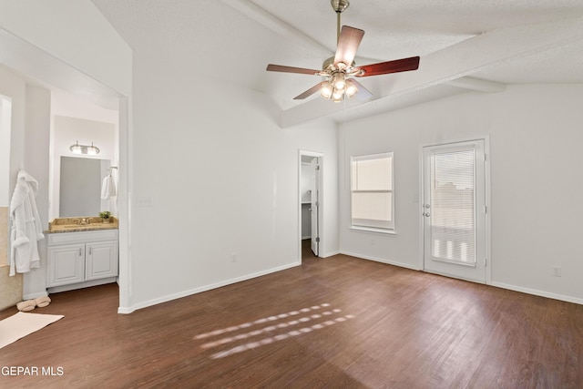 unfurnished bedroom featuring wood finished floors, connected bathroom, a spacious closet, and baseboards