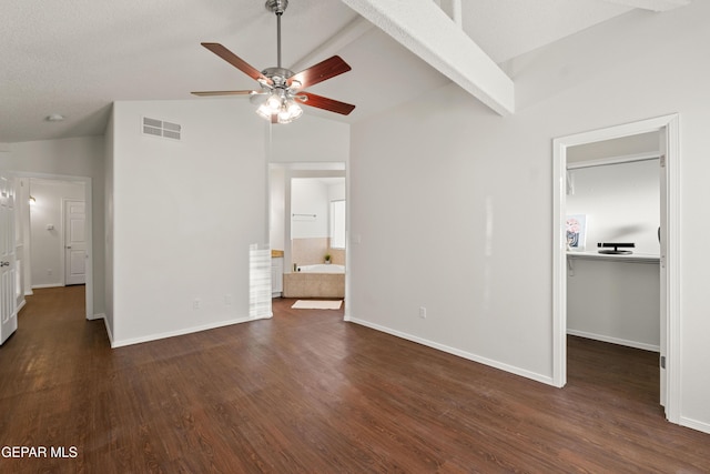 unfurnished bedroom featuring a walk in closet, dark wood finished floors, baseboards, and high vaulted ceiling