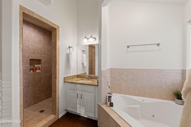 full bathroom featuring a jetted tub, vanity, wood finished floors, and a tile shower