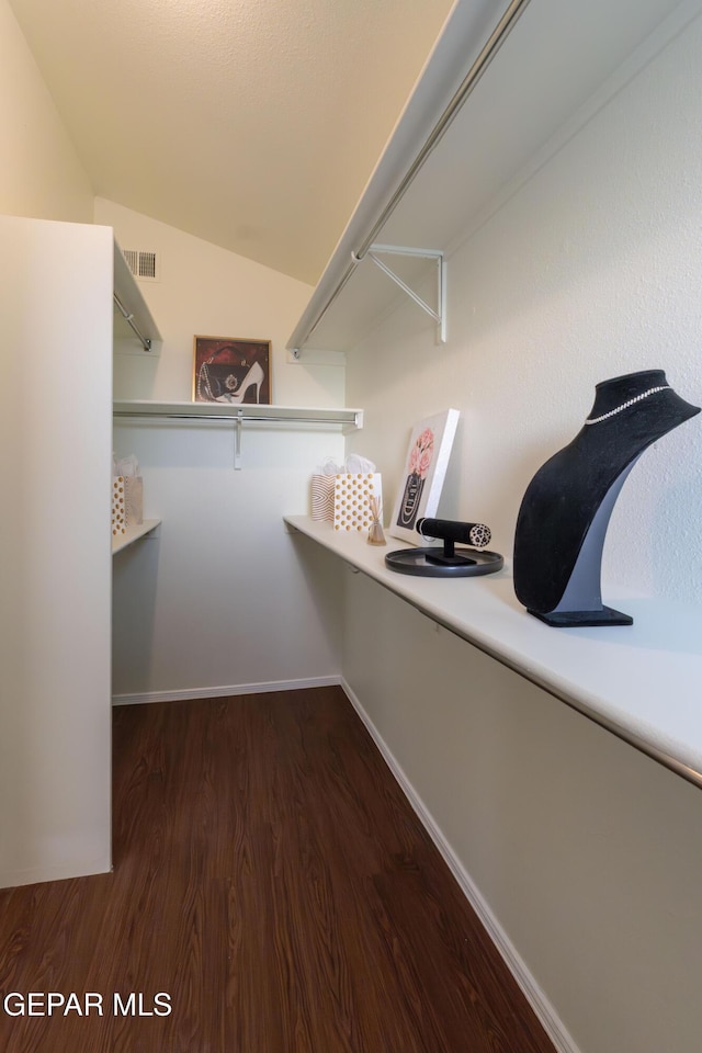 spacious closet featuring dark wood-type flooring and vaulted ceiling