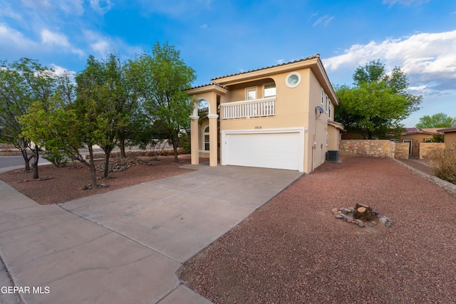 mediterranean / spanish home with a balcony, an attached garage, driveway, stucco siding, and central AC