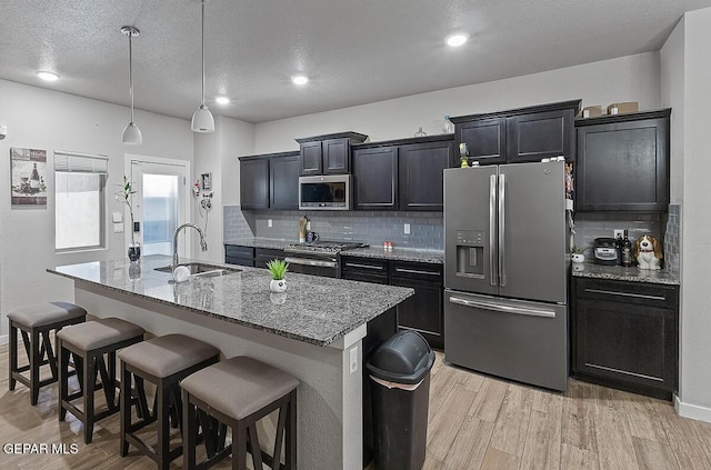 14840 Pebble Hills Blvd, El Paso, TX 79938 - kitchen with appliances with stainless steel finishes, a sink, a kitchen island with sink, light wood-style flooring, and recessed lighting