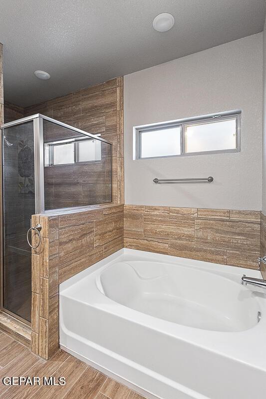 14840 Pebble Hills Blvd, El Paso, TX 79938 - full bath featuring a shower stall, a bath, wood finished floors, and a textured ceiling
