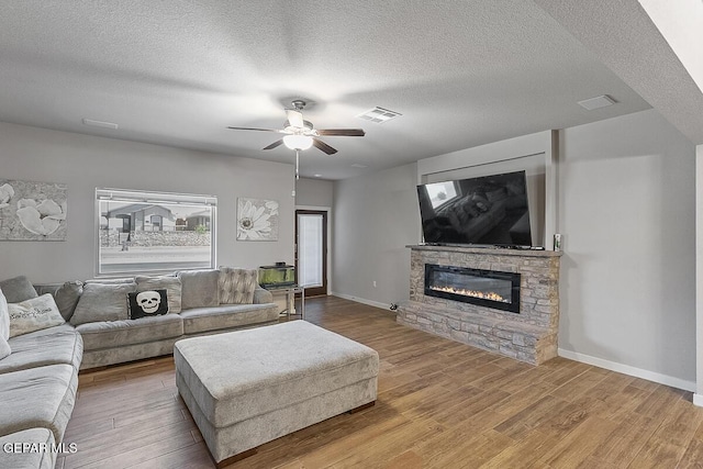 14840 Pebble Hills Blvd, El Paso, TX 79938 - living room featuring wood finished floors, a fireplace, a ceiling fan, baseboards, and a textured ceiling