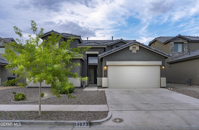 13673 Samlesbury Ave, Horizon City, TX 79928 - view of front of house with an attached garage, a tiled roof, stucco siding, and concrete driveway