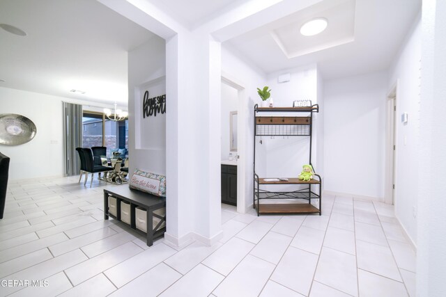 13673 Samlesbury Ave, Horizon City, TX 79928 - hallway featuring a chandelier, a tray ceiling, and light tile patterned floors