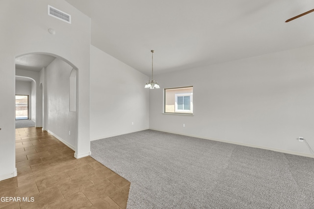 unfurnished room featuring vaulted ceiling, carpet flooring, arched walkways, baseboards, and a chandelier
