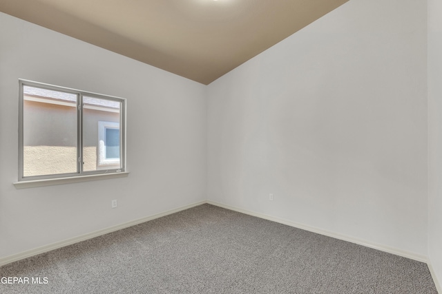 carpeted empty room featuring baseboards and lofted ceiling