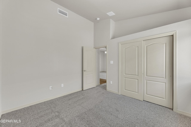 unfurnished bedroom with carpet floors, vaulted ceiling, baseboards, and a closet