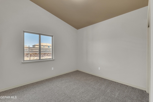 empty room featuring carpet flooring, lofted ceiling, and baseboards