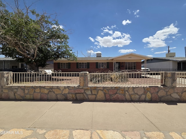 ranch-style home featuring brick siding and a fenced front yard