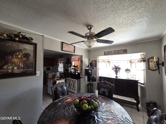 dining area with light tile patterned floors, a textured ceiling, a ceiling fan, and ornamental molding