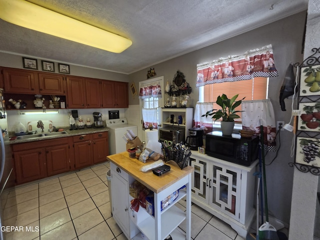 kitchen with a sink, black microwave, open shelves, washing machine and dryer, and light tile patterned flooring