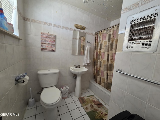 bathroom featuring tile walls, tile patterned floors, toilet, shower / bath combo, and a sink