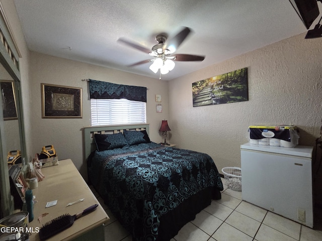 bedroom with a textured wall, light tile patterned floors, ceiling fan, and a textured ceiling