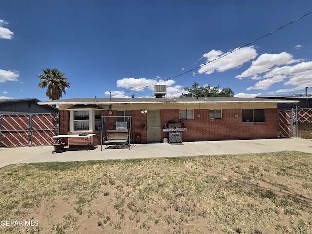 rear view of property featuring a patio, brick siding, central AC, and fence