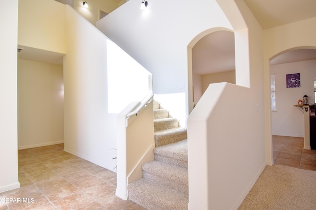 12093 Rathmore Dr, El Paso, TX 79928 - stairway with arched walkways, tile patterned floors, and baseboards