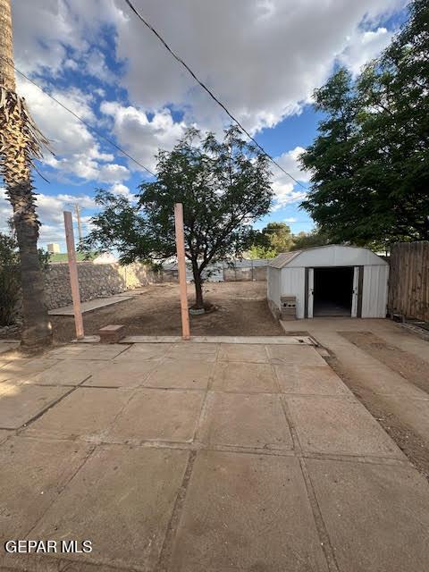 view of patio / terrace with a storage unit, a fenced backyard, and an outdoor structure