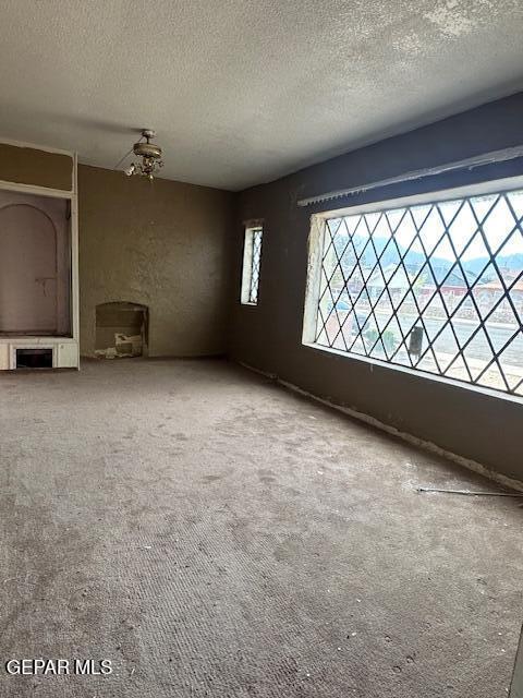 unfurnished living room featuring a textured ceiling and carpet