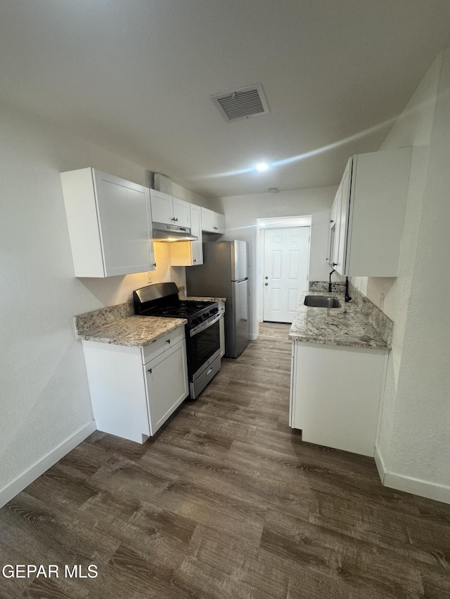 3512 Kemp Ave, El Paso, TX 79904 - kitchen featuring stainless steel appliances, under cabinet range hood, dark wood-style flooring, white cabinets, and light stone counters