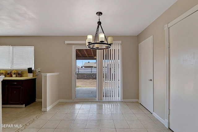 entryway featuring a chandelier, light tile patterned flooring, and baseboards