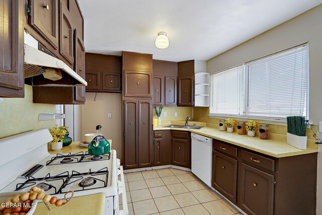 kitchen featuring white appliances, under cabinet range hood, a sink, and light countertops