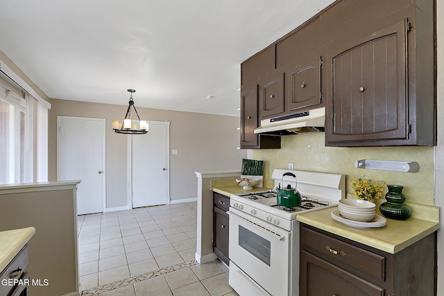 kitchen featuring under cabinet range hood, white gas range, dark brown cabinetry, and light countertops