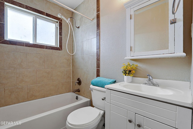 bathroom featuring toilet, a textured wall, shower / bathtub combination, and vanity